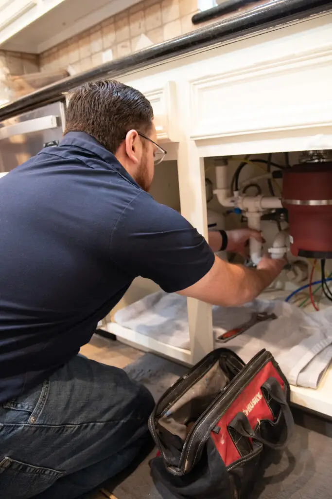 First Service Plumber working under a sink